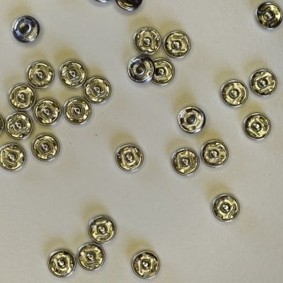 Botões de pressão metálicos prateados espalhados sobre fundo branco