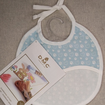 Babete para bebé azul com padrão de patas e etiqueta DMC