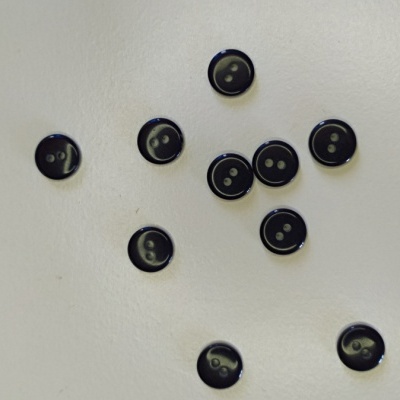 Dez botões pretos pequenos com dois furos sobre fundo branco