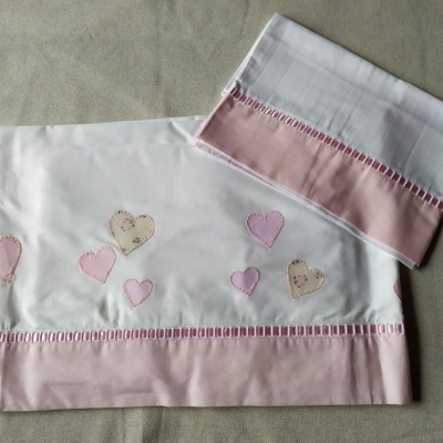 Jogo de cama branco com estampas de corações e barra rosa