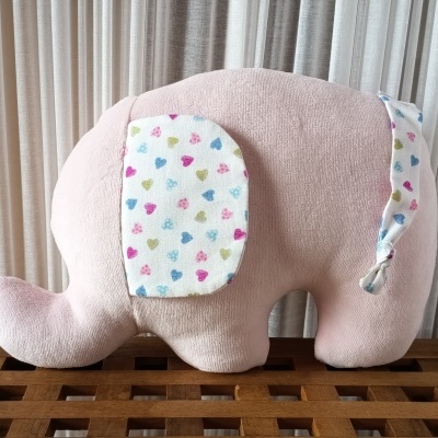 Pelúcia de elefante rosa com orelha e rabo estampados com corações coloridos