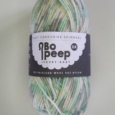 Novelo de lã para bebé em tons de verde, azul e bege com etiqueta preta