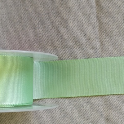 Rolo de fita verde claro sobre tecido bege com texto 'Verde'