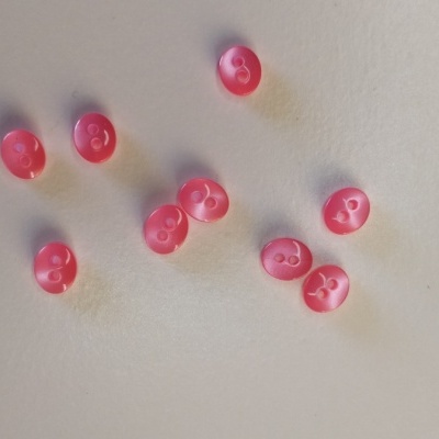 Botões redondos cor-de-rosa com dois furos sobre superfície branca
