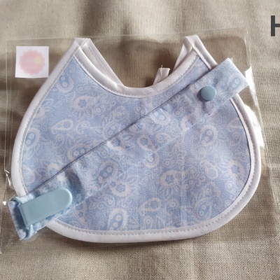Babete azul com padrão de corações e alça azul com botão e clip