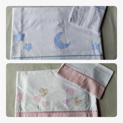 Lençóis infantis bordados com motivos de lua, estrelas e corações em azul e rosa