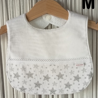 Babete de bebé branco com estrelas cinzentas pendurado num cabide de madeira