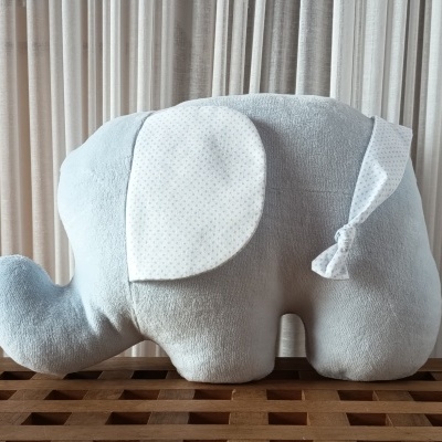 Pelúcia elefante azul claro com detalhes brancos e azuis.