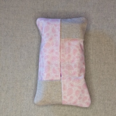 Bolsa almofadada rosa e bege com padrão de folhas sobre tecido cinzento
