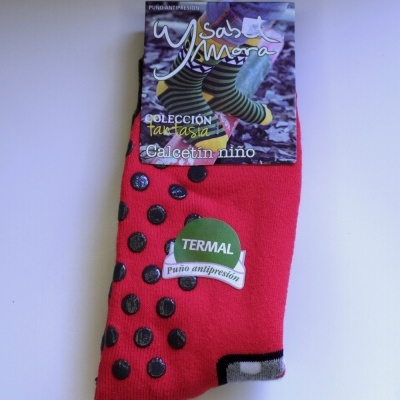 Meias vermelhas para criança com pontos antiderrapantes pretos e embalagem Ysabel Mora.