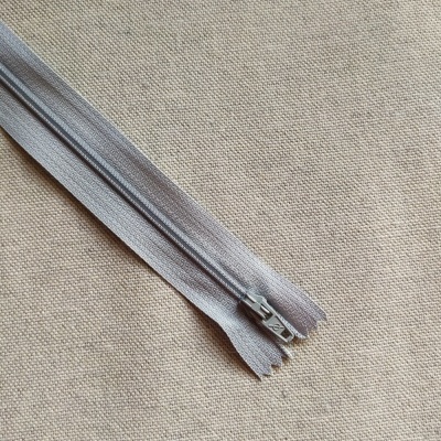 Fecho éclair cinzento claro sobre tecido bege com etiqueta Cor 729.