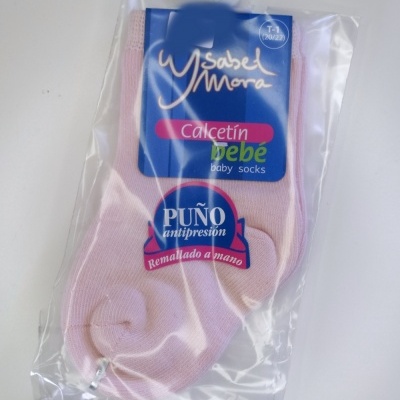 Meias de bebé cor de rosa embaladas com etiqueta com texto em espanhol