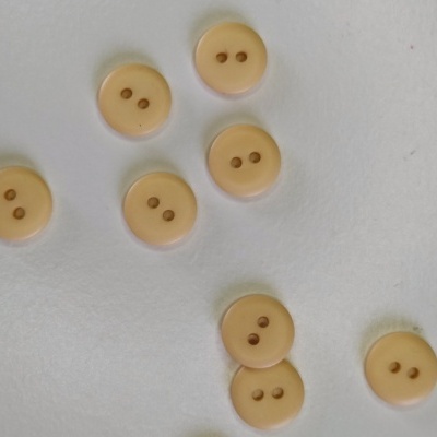 Botões redondos bege clara com dois orifícios sobre fundo branco