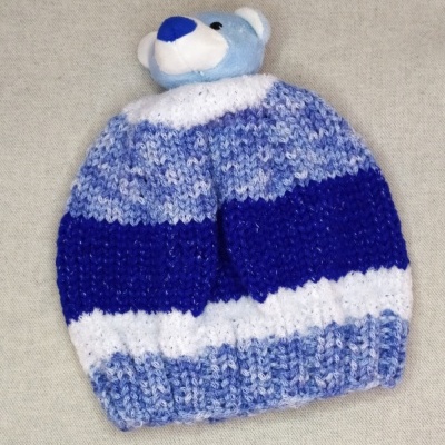 Gorro de malha azul e branco com ursinho de peluche azul no topo