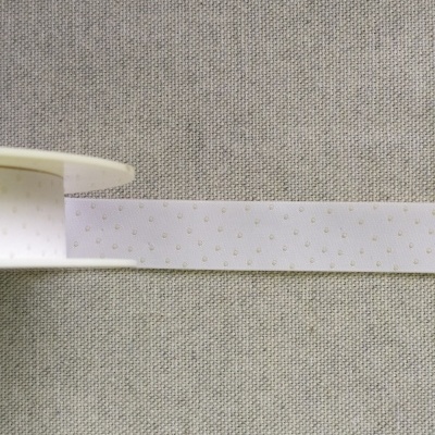 Fita branca com pintas bege sobre tecido cinza claro