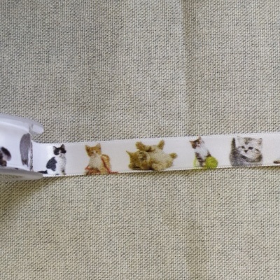 Fita decorativa branca com estampas de gatos coloridos sobre tecido bege