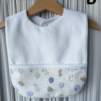 Babete branco de bebé com padrão de coelhos e balões azul em cabide de madeira