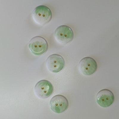 Botões redondos esverdeados com relevo branco e dois furos dourados sobre fundo branco.