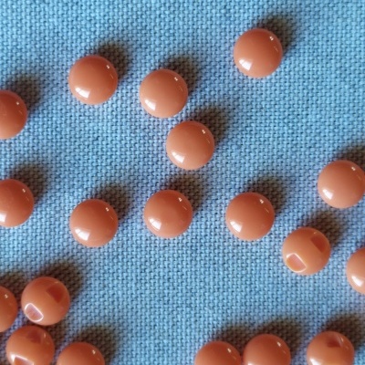 Contas plásticas laranja sobre fundo azul com texto 'Laranja'