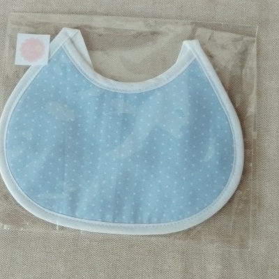Babete azul claro com pontos brancos embalada em saco plástico