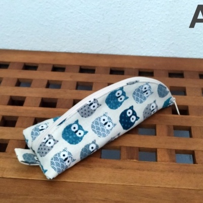 Estojo branco com corujas azuis e cinzentas sobre madeira com padrão quadrado