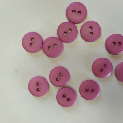 Doze botões rosa com dois buracos sobre fundo branco