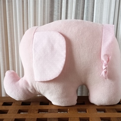 Almofada elefante rosa com orelhas e cauda de tecido com padrão de pontos.