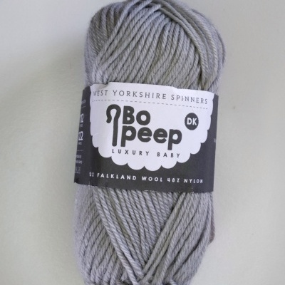 Novelo de lã cinzenta clara com etiqueta preta e branca com texto e fundo branco