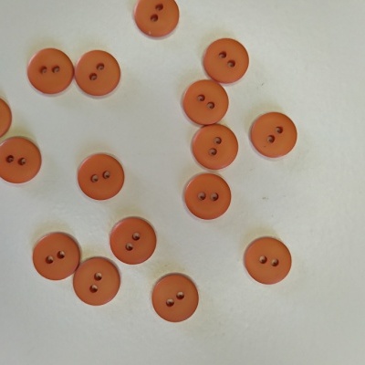 Botões laranja redondos com dois furos em superfície branca