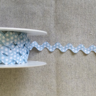 Fita azul com pintas brancas em rolo sobre tecido bege