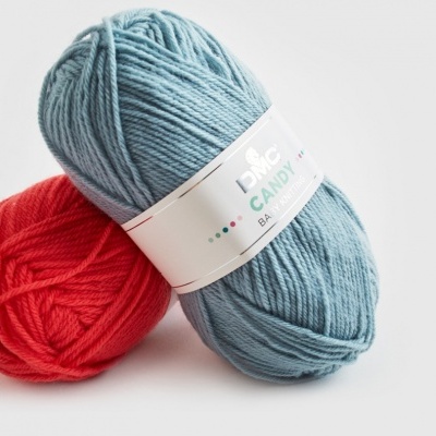 Novelos de lã azul claro e vermelho, novelo azul com rótulo branco escrito DMC CANDY