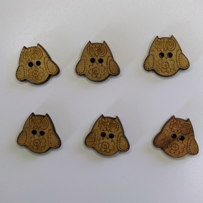 Seis botões de madeira em forma de cão com detalhes gravados sobre superfície branca