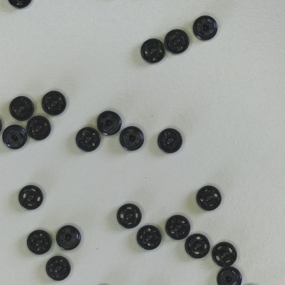 Botões pretos redondos com quatro furos sobre fundo branco