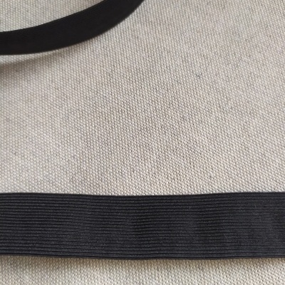 Fita elástica preta de 25 mm sobre fundo bege