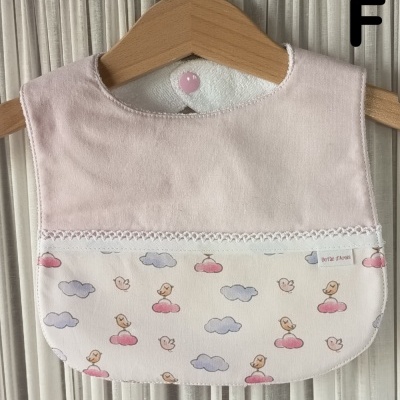 Babete rosa claro com padrão de nuvens e pássaros