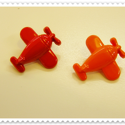 Dois brinquedos pequenos de avião em plástico vermelho e laranja