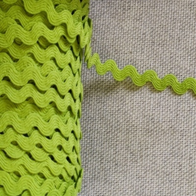 Rolo de fita zig-zag verde fluorescente num carretel branco sobre tecido cinzento