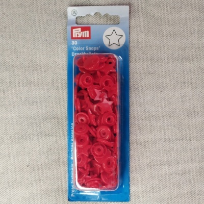 Pacote de botões de pressão vermelhos PRYM sobre tecido bege