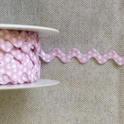 Fita ziguezague rosa com bolinhas brancas sobre tecido cinza