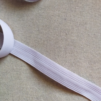 Rolo de fita elástica branca canelada de 18 mm sobre tecido bege