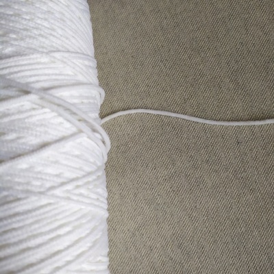 Rolo de cordão branco fino sobre superfície cinza texturada