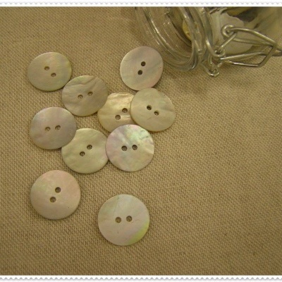 Botões redondos de madre-pérola sobre tecido bege com corrente metálica