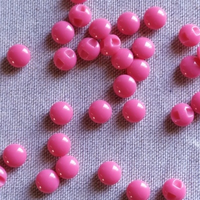 Bolinhas de plástico cor de rosa forte sobre tecido cinzento