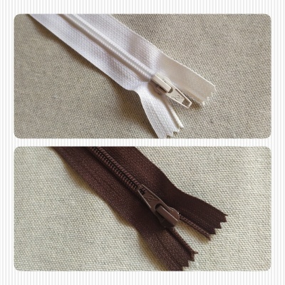 Fechos éclair branco e castanho sobre tecido bege