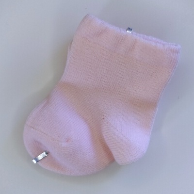 Meia cor-de-rosa clara de bebé em fundo branco