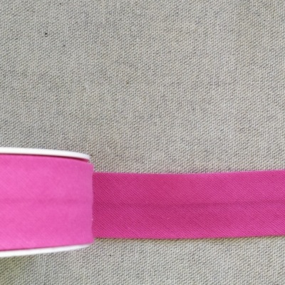 Fita têxtil rosa forte enrolada em carretel sobre tecido cinzento