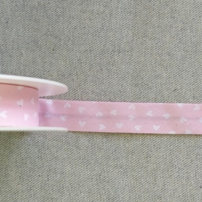 Fita rosa com corações brancos em carretel