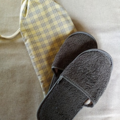 Chinelos cinza escuro felpudos e saco de pano amarelo com padrão de riscas