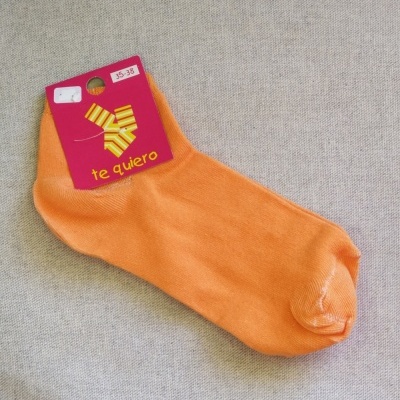 Meia laranja com etiqueta rosa 'te quiero' sobre tecido cinzento