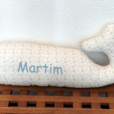 Pelúcia em forma de baleia branca com padrão floral e nome Martim
